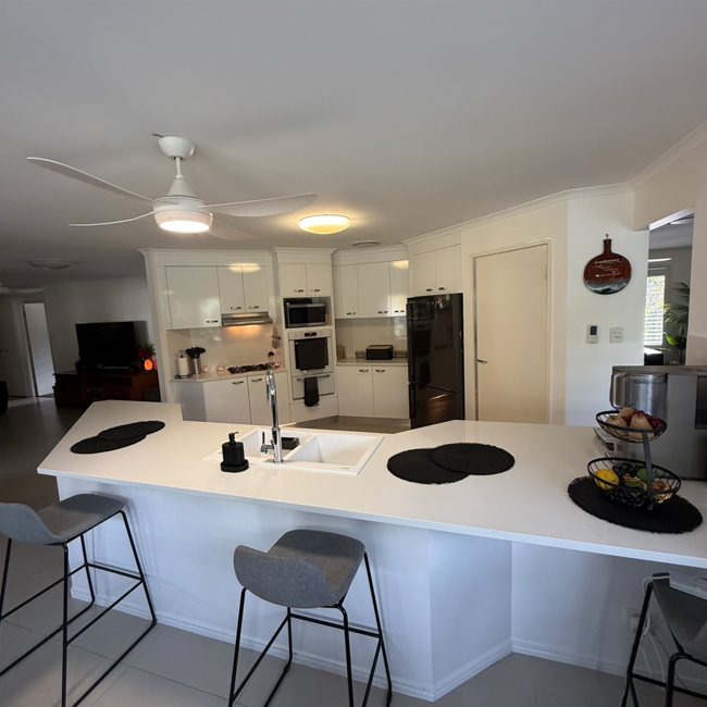 Brisbane Benchtops kitchen renovation featuring a large white island benchtop and bar seating in Brisbane’s western suburbs
